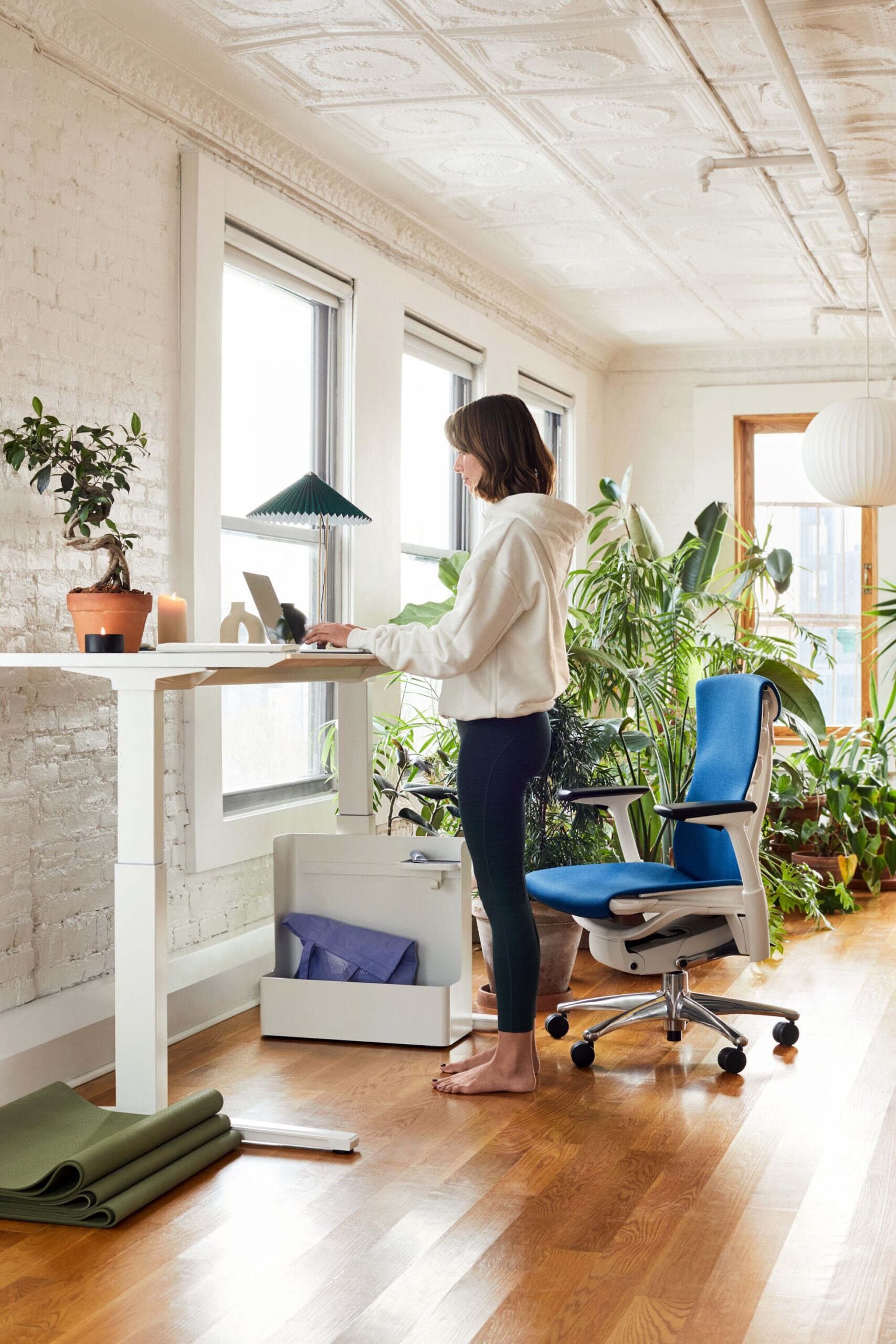 Escritório em casa com mesa com regulagem de altura branca e cadeira ergonômica