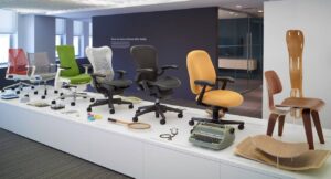 Gerações de cadeiras Herman Miller expostas em um show room. Da esquerda para a direita: Sayl, Setu, Embody, Mirra, Aeron, Ergon e Lounge Wood Chair