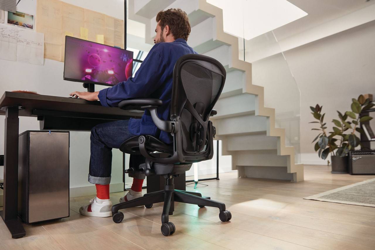 homem joga ao computador enquanto senta em uma cadeira aeron