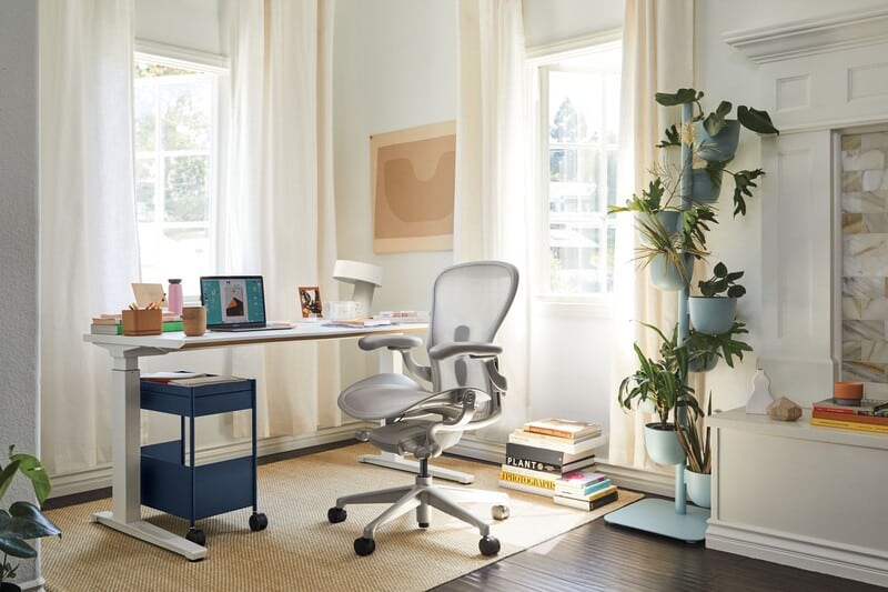 Escritório moderno com mesa, cadeira e plantas decorativas.