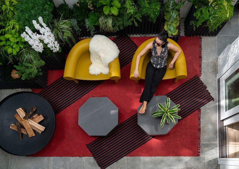 mulher sentada em uma área externa decorada com móveis da Herman Miller