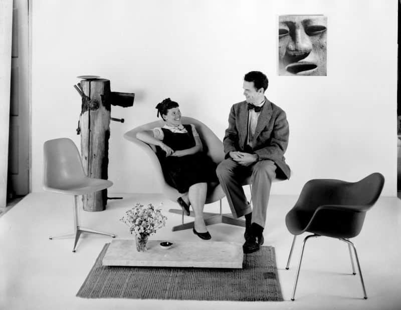 Charles e Ray Eames sentado em uma cadeira curvada com expressão de felizes