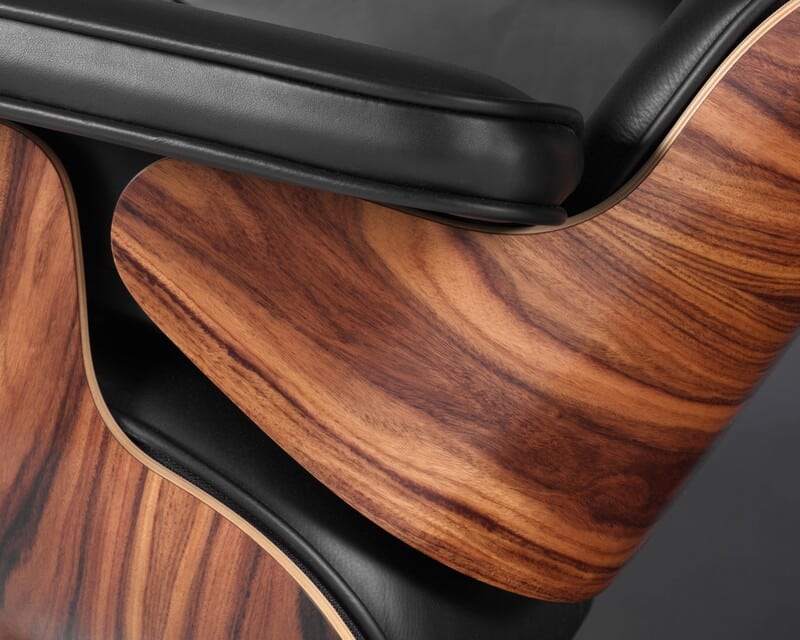 Detalhe de poltrona moderna com acabamento em madeira e couro preto.