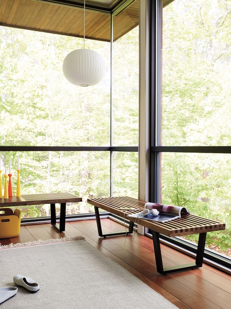 Sala com varanda, mesa de madeira e vista para árvores
