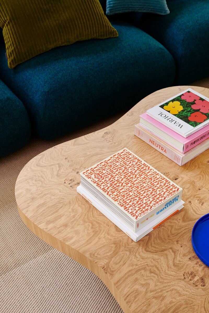 Mesa de centro com livros coloridos e almofadas verdinhas